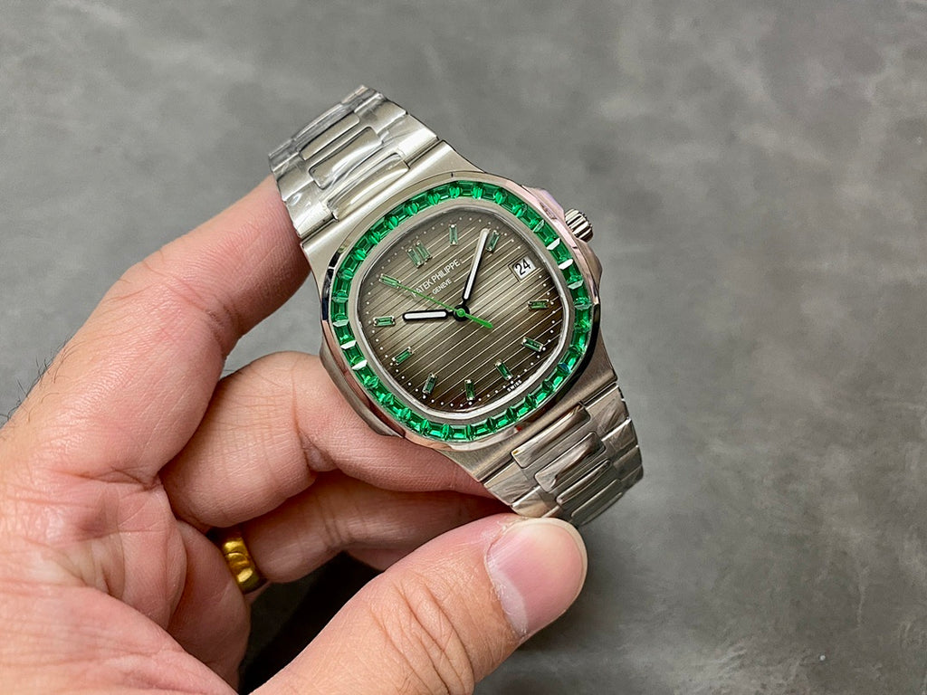 Patek Philippe watch with green bezel stones, silver bracelet, and gray dial