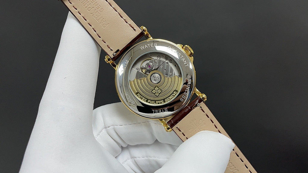 Patek Philippe watch with open back, gold-tone case, brown leather strap.