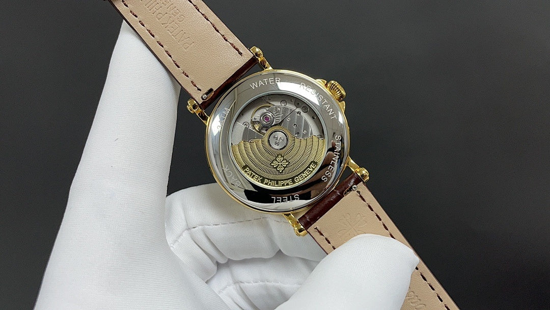 Patek Philippe watch with open back, gold-tone case, brown leather strap.