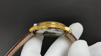 Patek Philippe watch case back with gold-tone finish and brown leather strap.