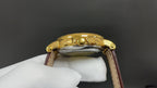 Patek Philippe watch back view, gold-tone case and brown leather strap.