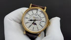 Patek Philippe watch with white dial, black Roman numerals, brown leather strap.