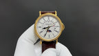 Patek Philippe watch front view, white dial with gold-tone case and brown strap.