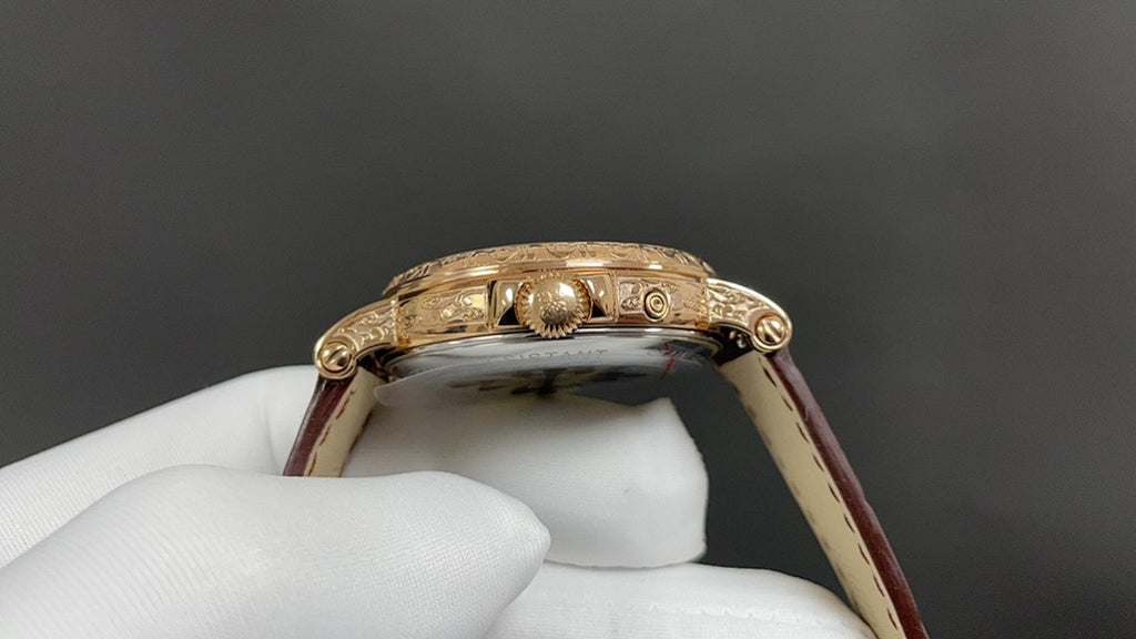 Patek Philippe watch case close-up showing gold bezel and crown, brown strap visible.
