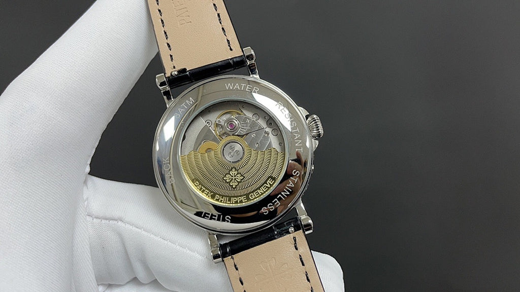 Patek Philippe watch caseback with exposed gears and engraved medallion, black strap