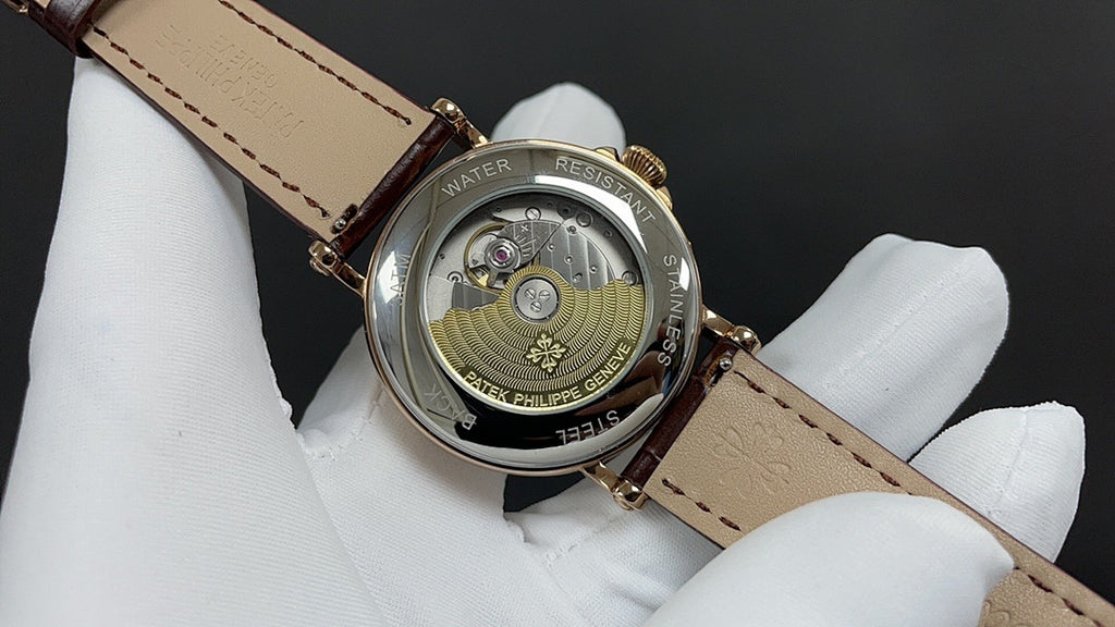 Patek Philippe watch case back with engraved details, gold tone, on brown leather strap