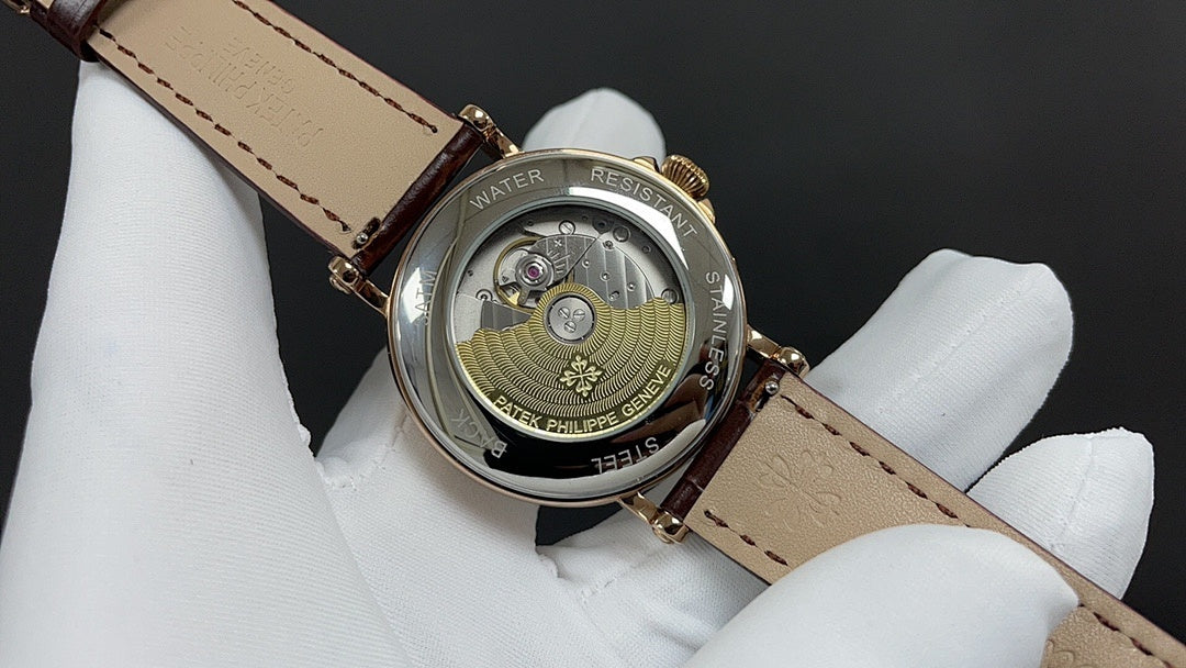Patek Philippe watch case back with engraved details, gold tone, on brown leather strap