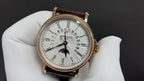 Patek Philippe wristwatch with white dial, gold case, dark brown leather strap on glove