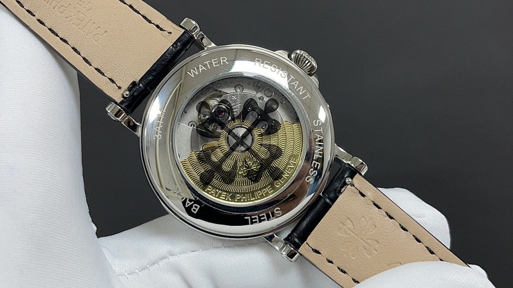 Patek Philippe watch case back on black leather strap, engraved markings visible