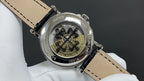 Patek Philippe watch case back on black leather strap, engraved markings visible