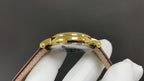 Patek Philippe wristwatch with gold-tone case and brown leather strap, close-up of round case