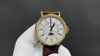 Patek Philippe wristwatch with gold-tone case, white dial, brown leather strap and moon phase
