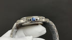 Steel wristwatch case back with blue center medallion and metal bracelet links