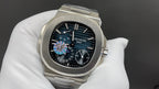 Steel wristwatch with black dial, colored center motif, and visible subdials on bracelet