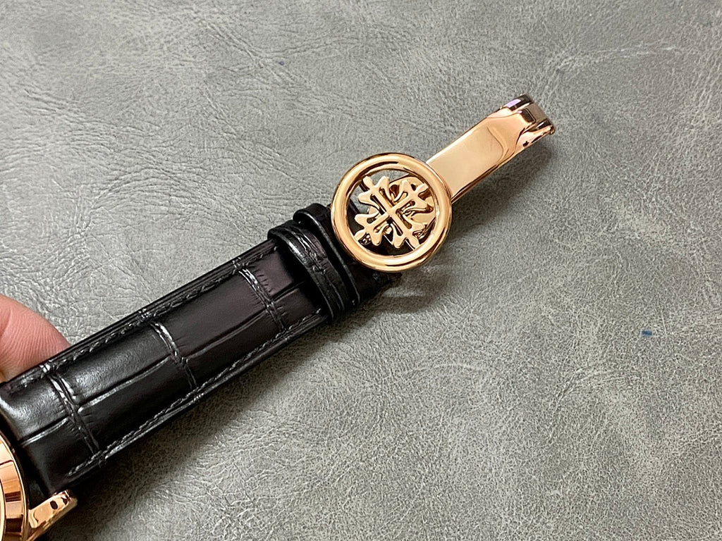 Rose-gold watch crown with engraved emblem on black leather strap