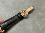 Rose-gold watch crown with engraved emblem on black leather strap