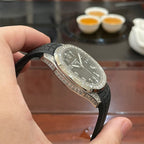 Patek Philippe watch with black dial, black rubber strap, and diamond-studded bezel