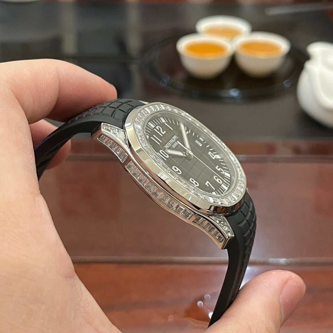 Patek Philippe watch with black dial, black rubber strap, and diamond-studded bezel