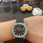 Patek Philippe watch on wrist with black rubber strap, black dial, and jeweled bezel