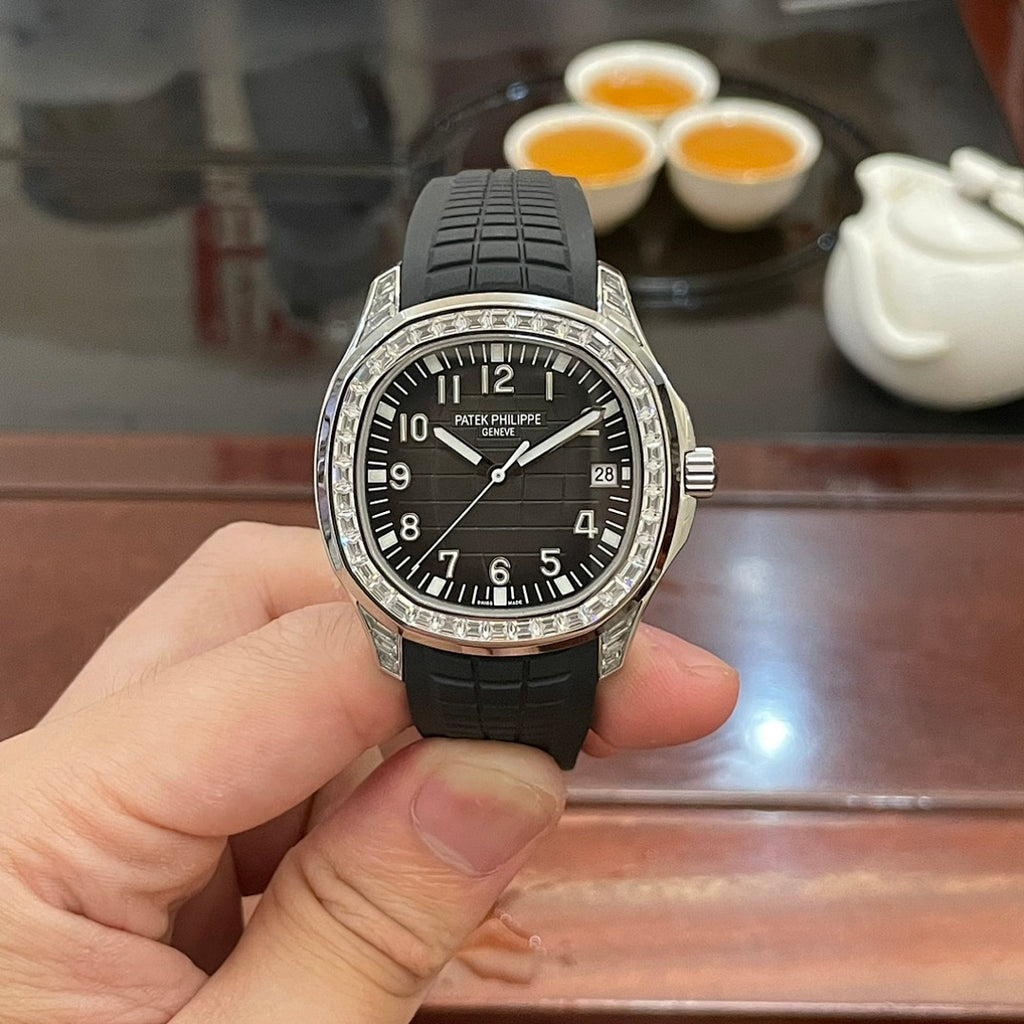 Patek Philippe watch front view with black dial, black rubber strap, and jeweled bezel