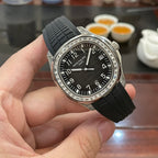 Patek Philippe watch with black dial, black rubber strap, and jeweled silver bezel