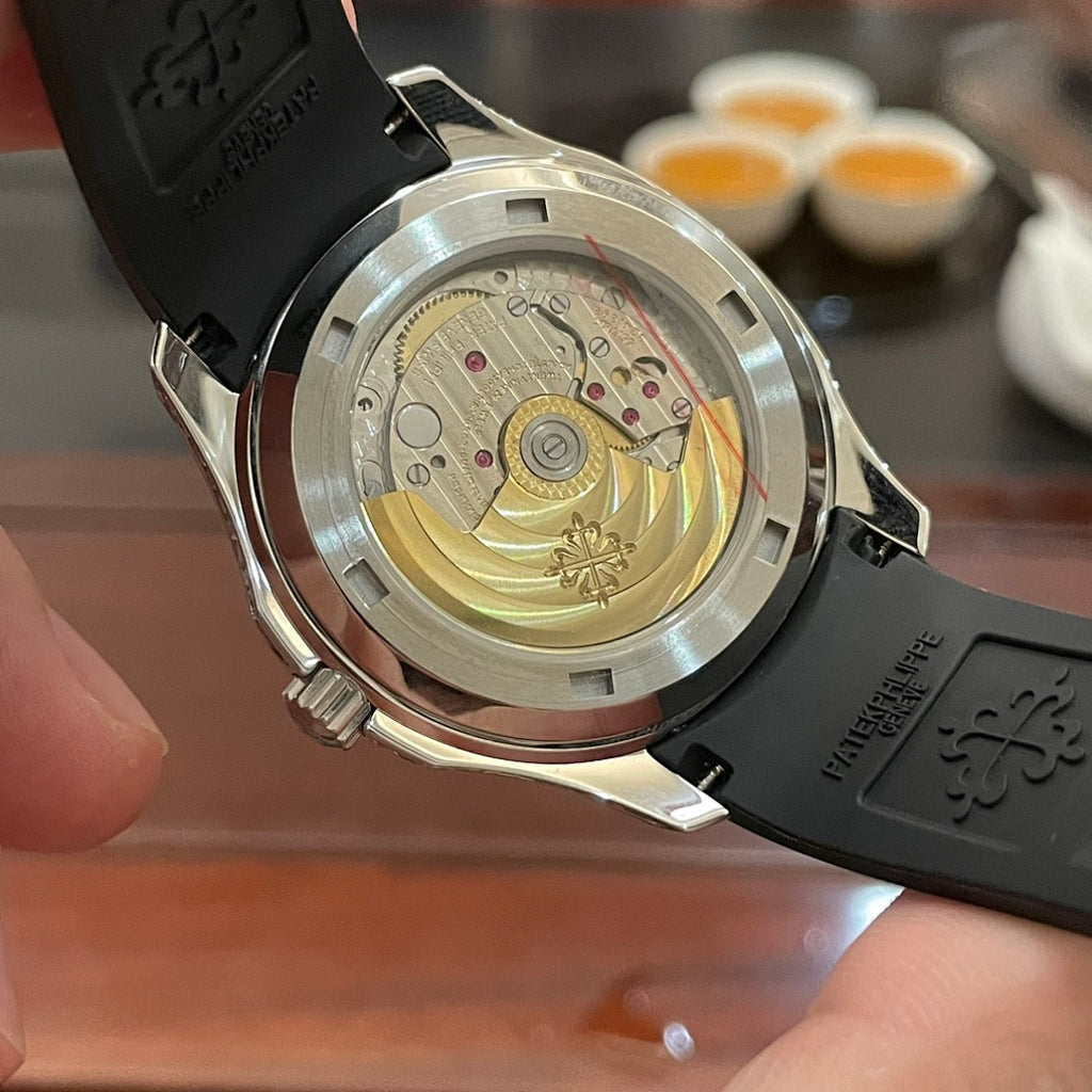 Patek Philippe wristwatch caseback with gold-toned movement and black silicone strap