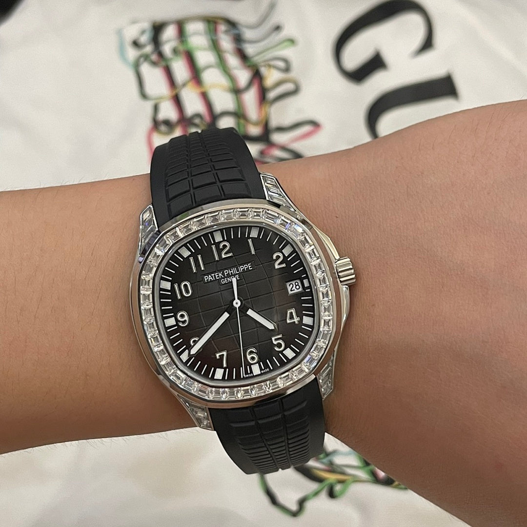 Patek Philippe wristwatch front with black dial, black rubber strap, silver bezel stones