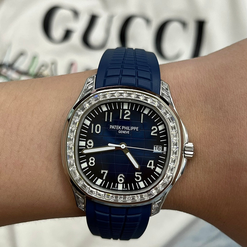 Luxury wristwatch on wrist with blue rubber strap, black dial, diamond bezel