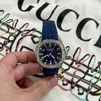 Luxury wristwatch with dark blue dial, black markers, and textured blue strap