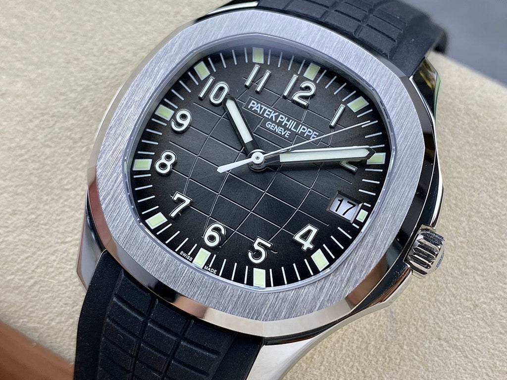 Patek Philippe wristwatch with black dial, silver case bezel, black rubber strap.