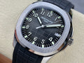 Patek Philippe wristwatch with black dial, silver case bezel, black rubber strap.