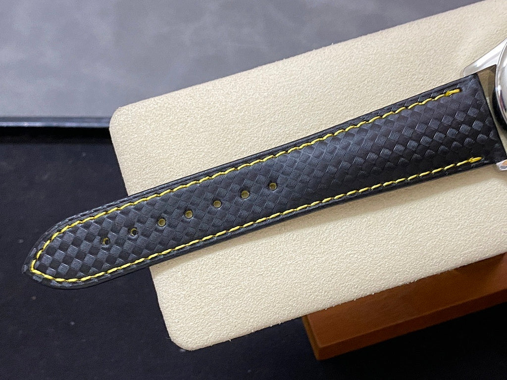 Black watch strap with subtle texture and bright yellow contrast stitching.