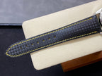 Black watch strap with subtle texture and bright yellow contrast stitching.