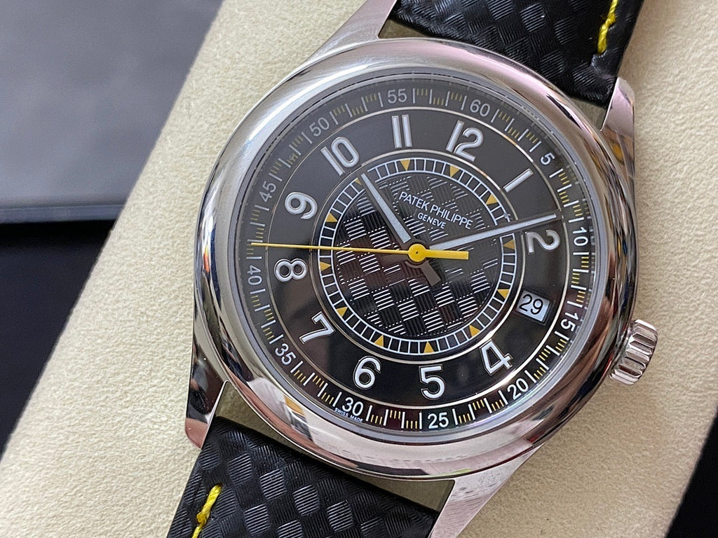 Luxury wristwatch with stainless case, dark dial, yellow hands, and black strap with yellow stitching.