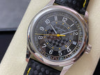 Luxury wristwatch with stainless case, dark dial, yellow hands, and black strap with yellow stitching.