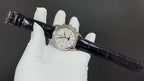 Patek Philippe watch on black leather strap held by white-gloved hands
