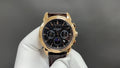 Patek Philippe wristwatch with dark dial, gold bezel, brown leather strap on glove
