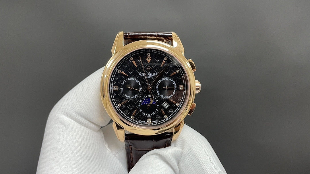 Patek Philippe wristwatch with dark dial, gold bezel, brown leather strap on glove
