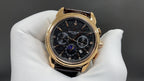Patek Philippe wristwatch front view, dark dial with subdials, brown leather strap