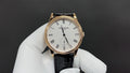 Patek Philippe wristwatch with white dial, black leather strap, and rose-gold case
