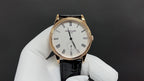 Patek Philippe wristwatch with white dial, black leather strap, and rose-gold case