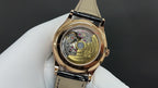 Patek Philippe wristwatch with exposed mechanical movement, gold case, and black strap