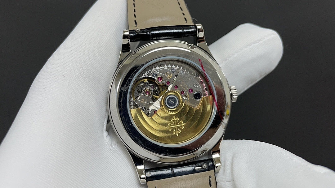 Wristwatch movement view with gold-toned gear and jeweled components under clear cover