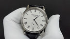 Wristwatch with white dial, Roman numerals, black leather strap, three-hand layout