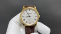 Patek Philippe watch with white dial, Roman numerals, gold case, brown leather strap