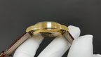 Patek Philippe watch case from above, gold bezel and brown leather strap ends