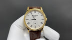Patek Philippe watch with white dial and black hands, gold case, brown leather strap