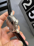 Patek Philippe wristwatch with silver case and black leather strap, crown visible