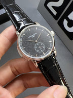 Patek Philippe wristwatch side view with black leather strap and dark gray dial