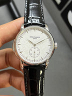 Patek Philippe watch with black leather strap and silver-tone case, white dial with subdial details
